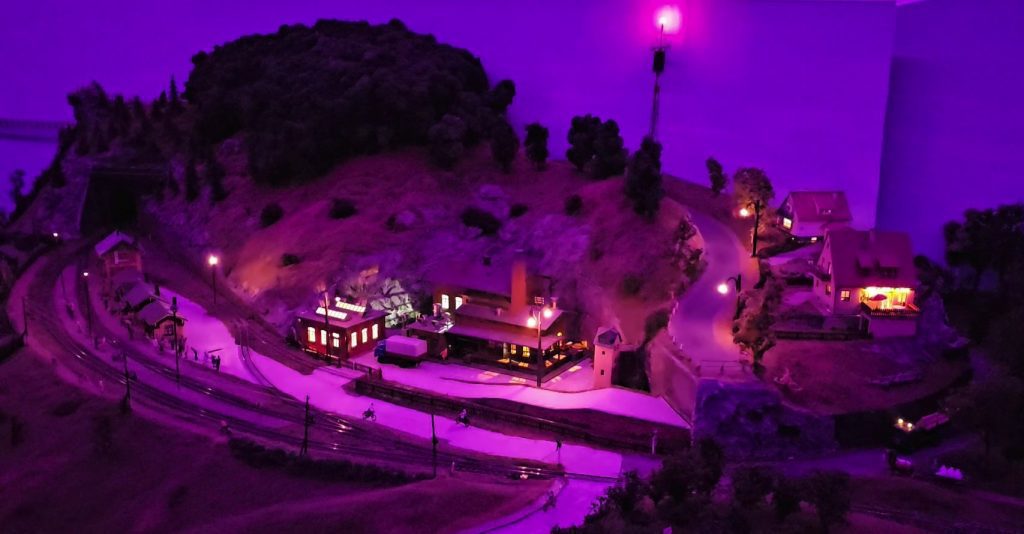 Auf diesem Bild ist das Modell einer Glockengießerei und zwei Einfamilienhäuser bei Nacht zu sehen. Die Gebäude sind jetzt Beleuchtet.